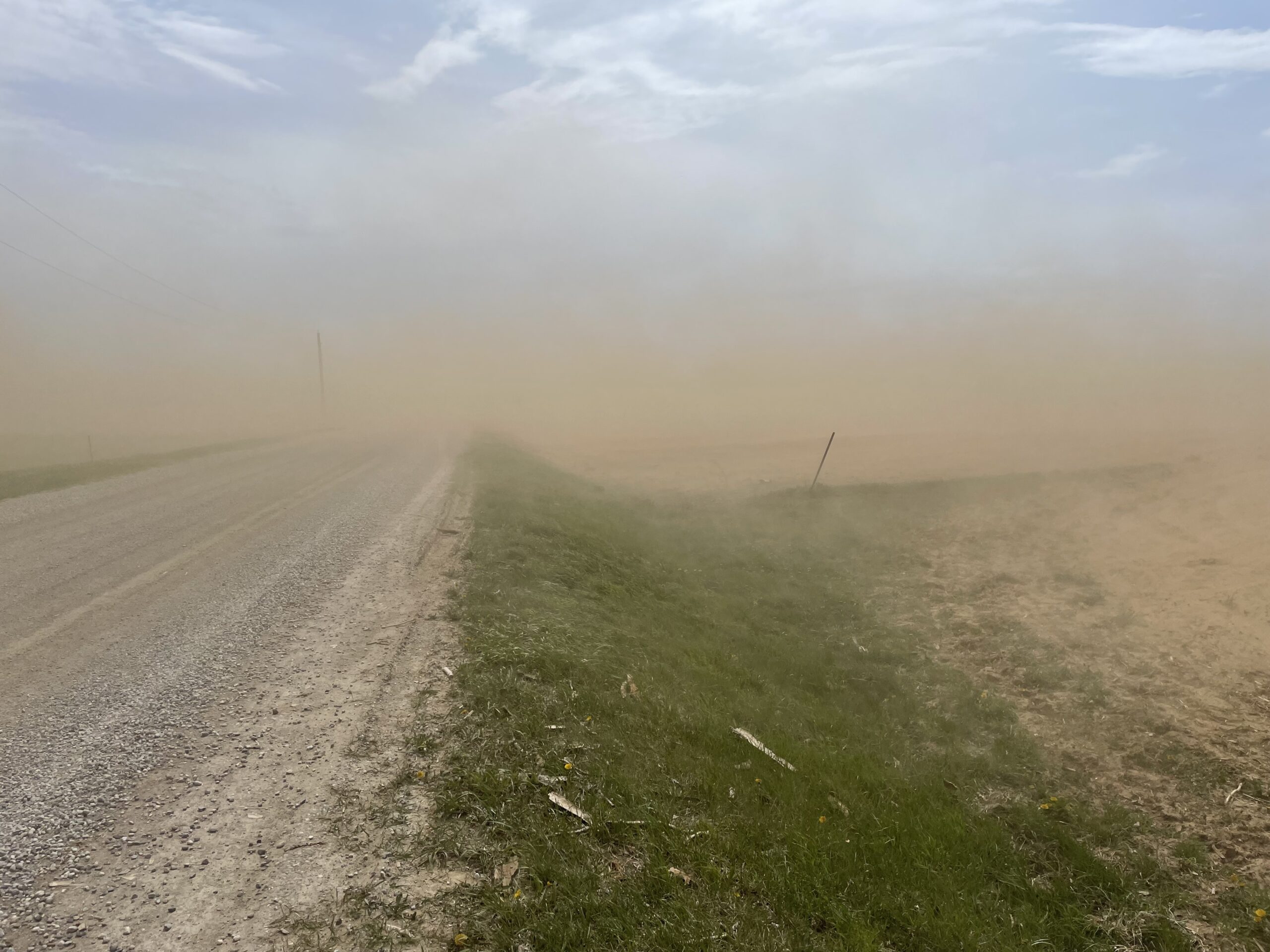 fine soil particles blowing off a field onto a rural highway