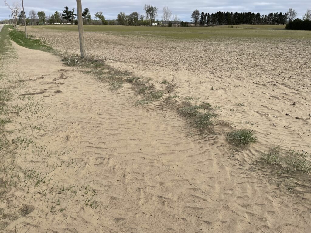 field with windblown soil in the ditch next to it